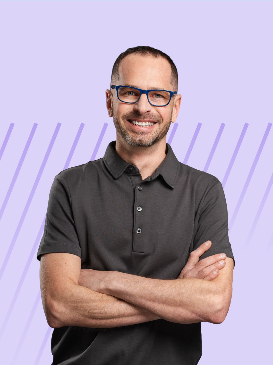 Man with glasses and a dark grey polo shirt smiling with arms crossed.