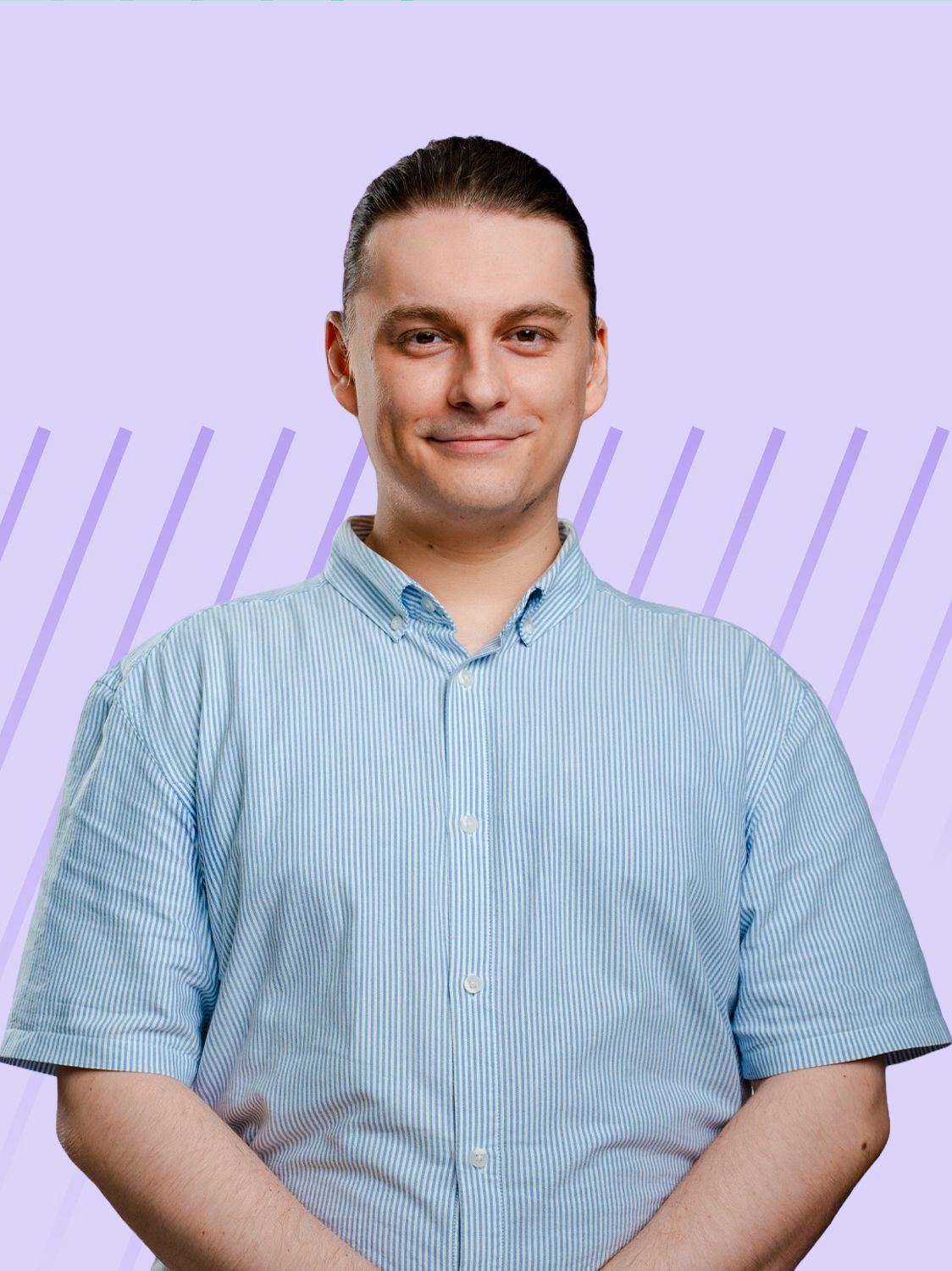 A man in a light blue shirt smiles, standing against a purple striped background.