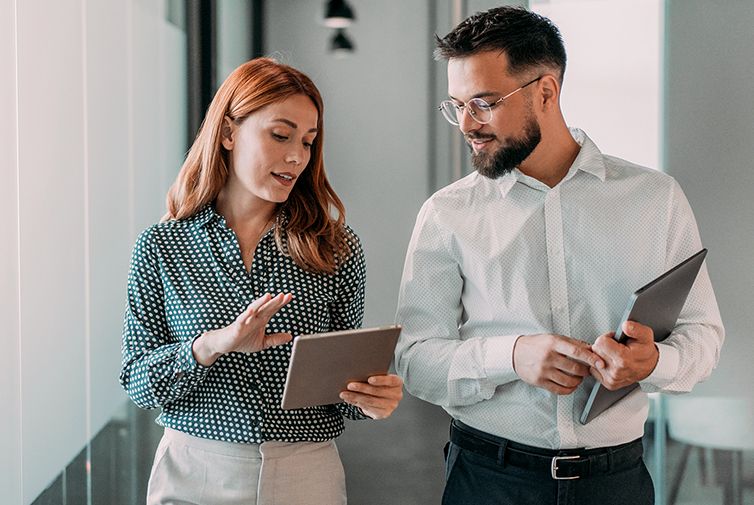 Two colleagues discussing work while looking at a tablet in an office.