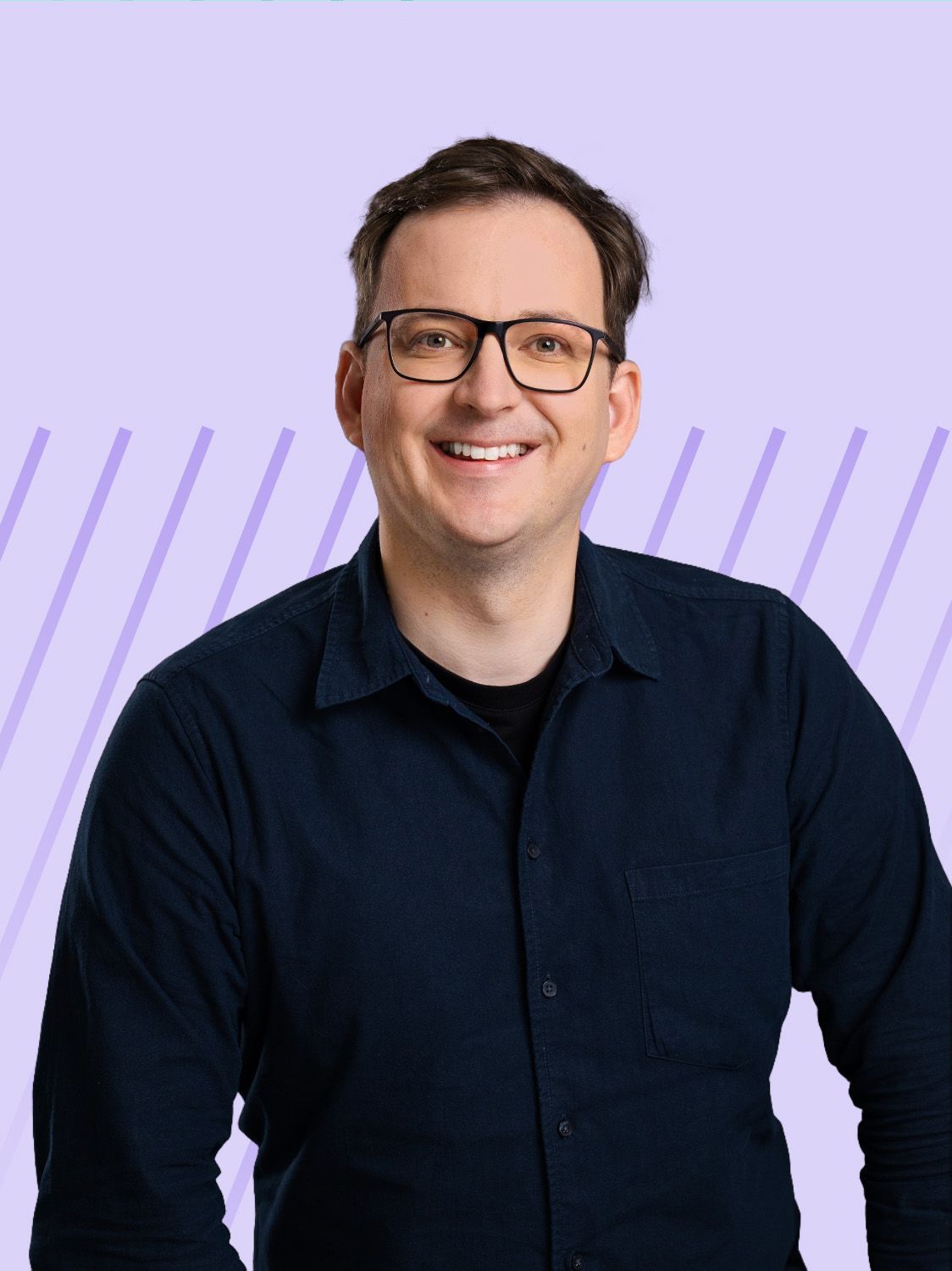 A smiling man with dark hair and glasses wearing a dark shirt.