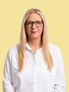 A woman with blonde hair and glasses wears a white shirt.