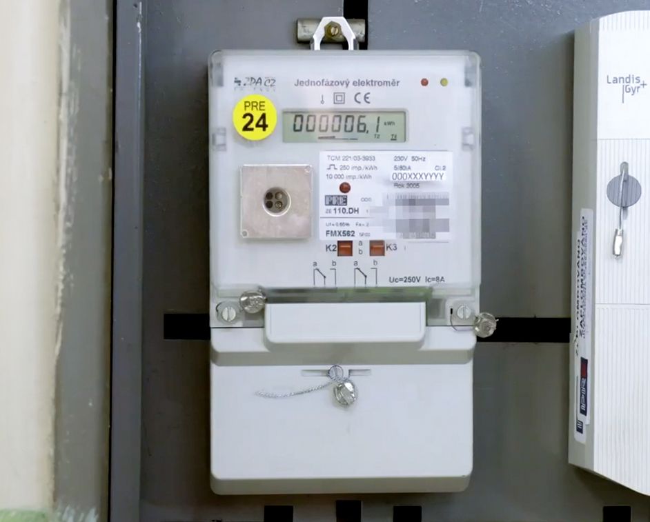 Close-up of a digital electricity meter with a numerical display and yellow sticker.