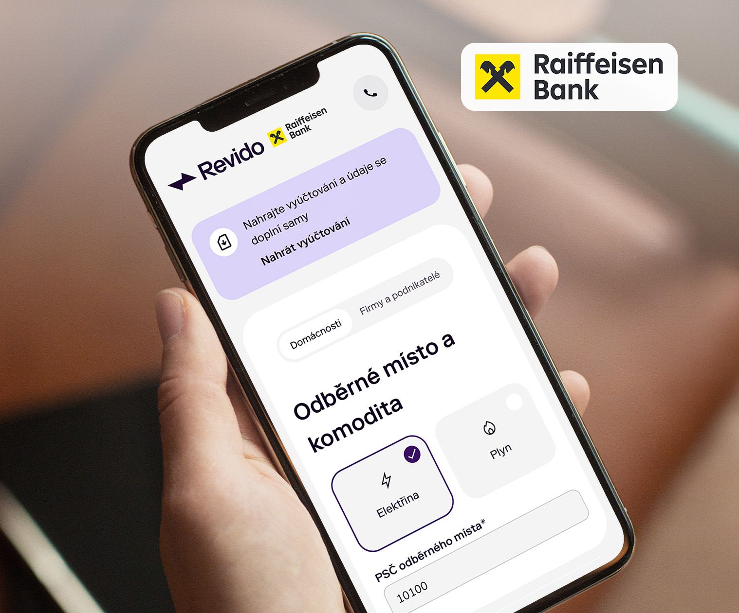 Hand holding smartphone displaying the Raiffeisen Bank 'Revido' mobile banking app interface.