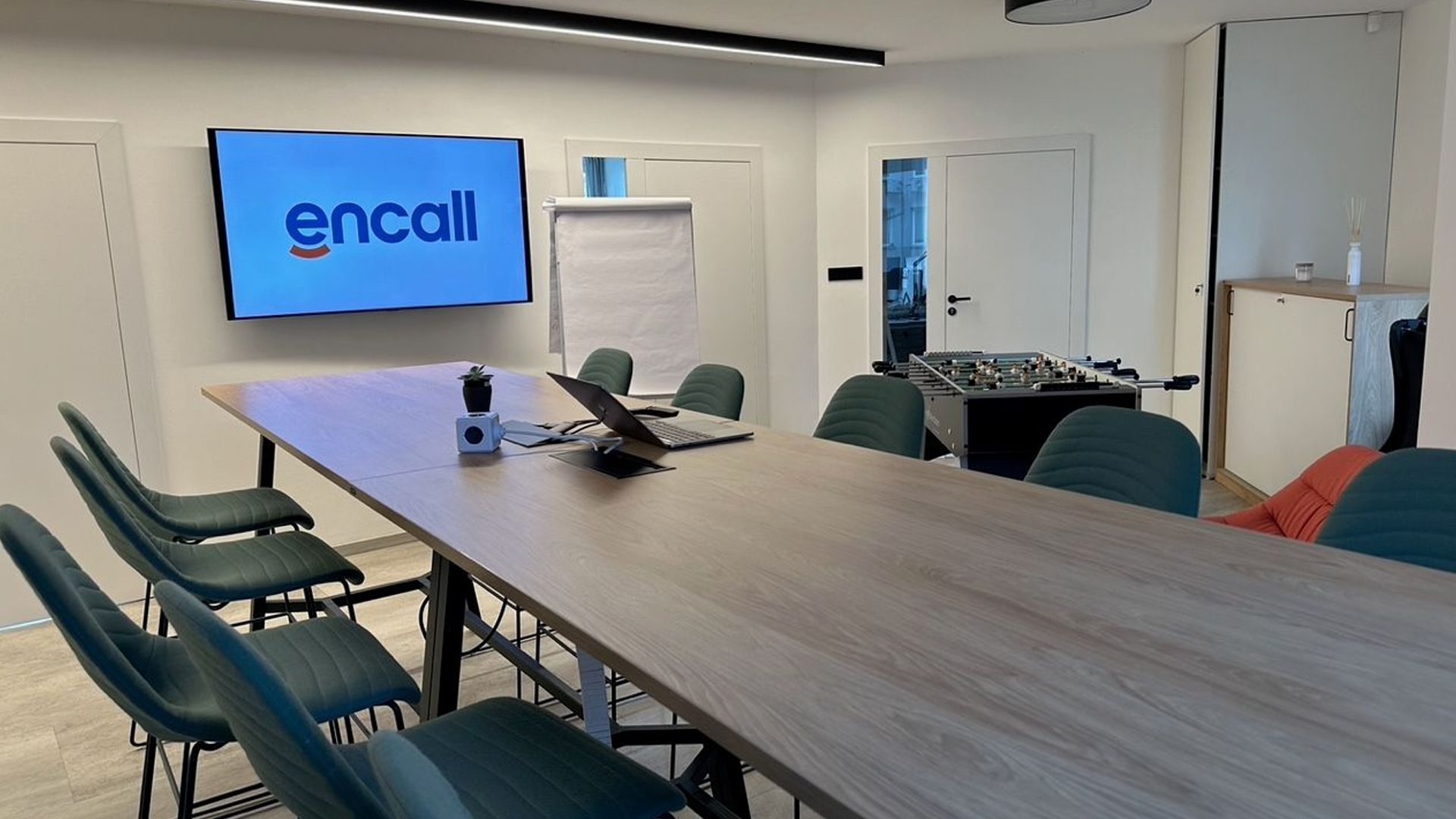 Modern meeting room with a large screen displaying the "encall" logo and a long conference table.